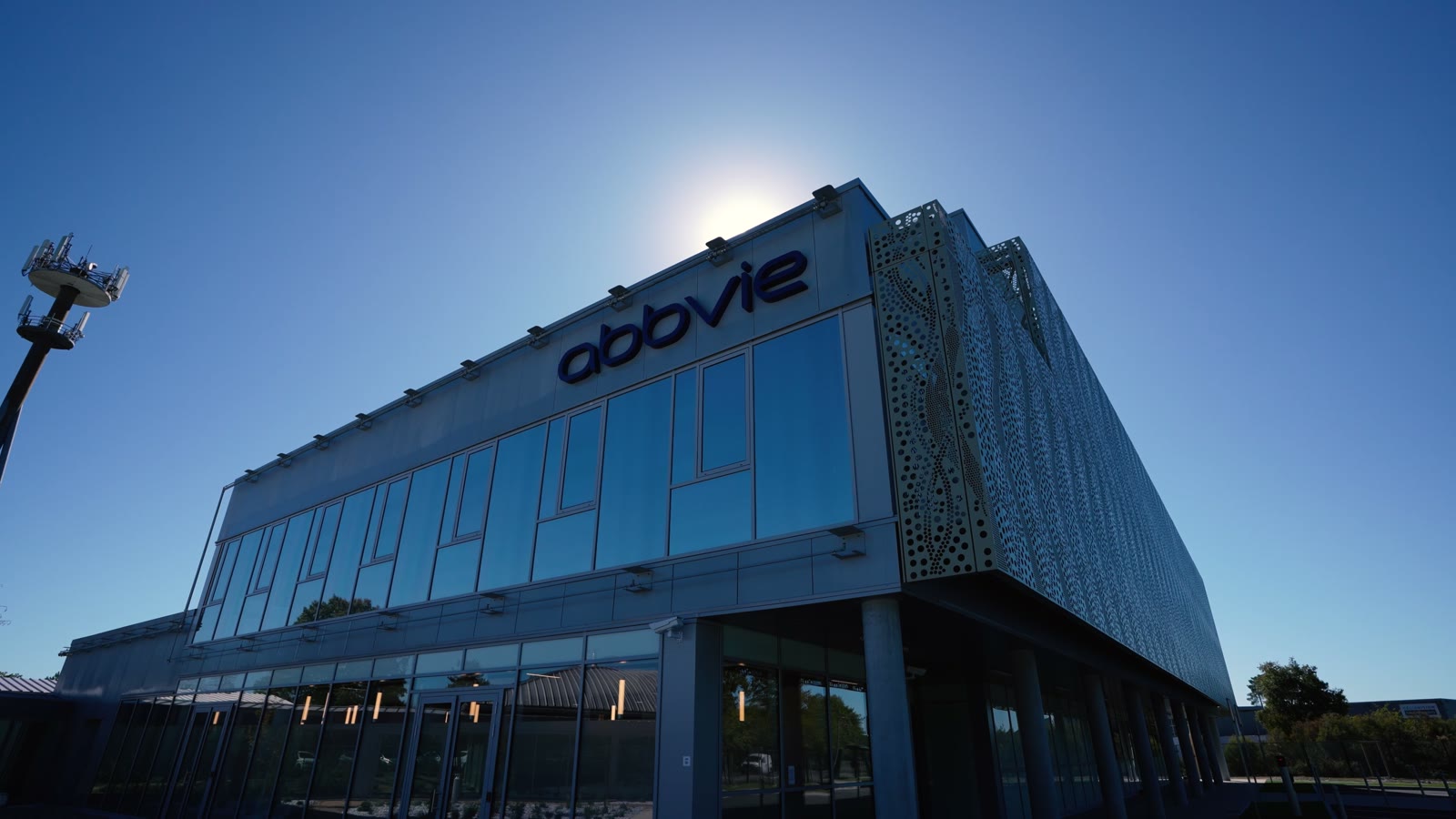 Façade vitrée du site AbbVie de Martillac en contre-plongée, soleil dans le cadre