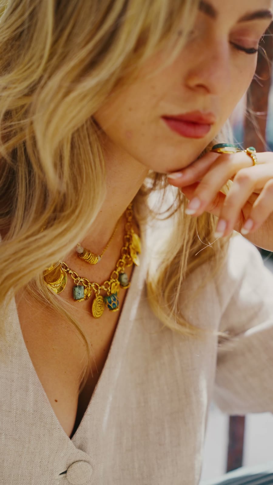 Gros plan sur un collier de pierres colorées et de médailles dorées Eiden, porté sur un gilet en lin